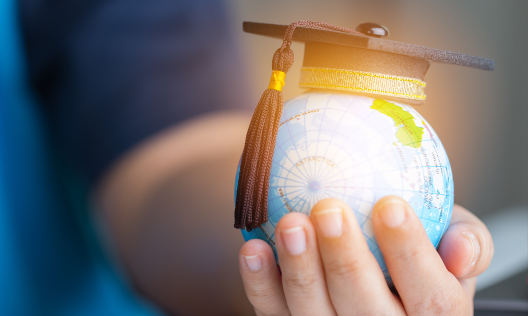 Child holding a Mini Globe with a Graduation Cap to promote Educational Articles